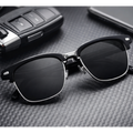 Black sunglasses on a textured surface with car keys and a phone in the background